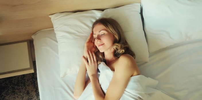 Young woman sleeping lying in bed on white soft comfortable pillow in bedroom at home