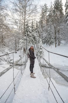 Woman in winter jacket walking in snowy winter forest, snowy winter day