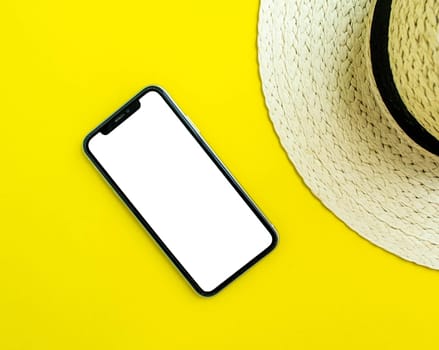 Mockup, smartphone and straw hat on yellow background. Summer vacation. Background for advertising.