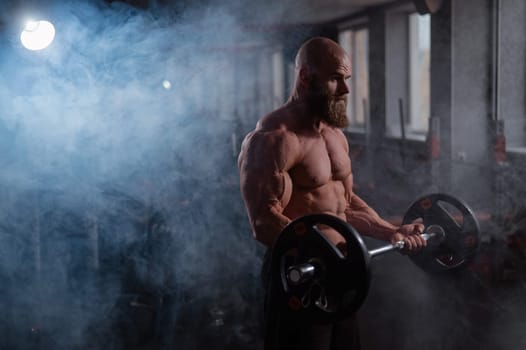 Caucasian bald topless man doing an exercise with a barbell in the gym. Bicep curls with weights