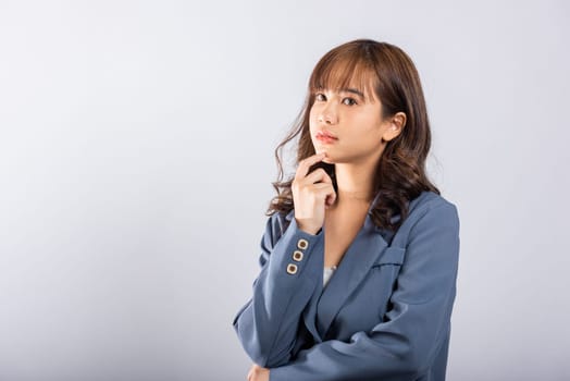 Portrait of an Asian business woman deep in thought thinking chin in her finger, pondering a question. Studio shot on white background with ample copy space, portraying her contemplative expression