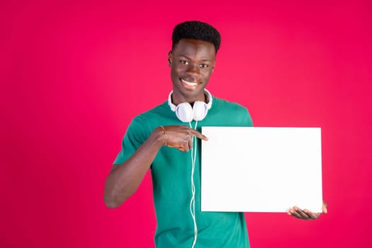 A man in a green shirt is holding a white sign and pointing to it. Concept of importance and guidance, as the man is directing someone towards the sign. The red background adds a bold