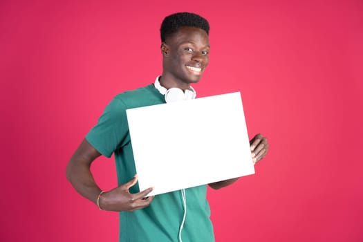 A young man is holding a white sign and smiling. The sign is blank, which could represent a blank slate or a new beginning