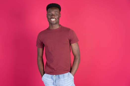 A man in a red shirt is smiling and standing in front of a red background. Concept of happiness and positivity