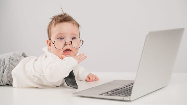 Cute baby in glasses and suit working on laptop