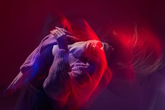 A young woman dances contemporary dances in blue and red light. Long exposure photo