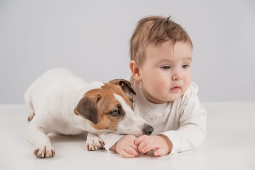 Cute baby boy and Jack Russell terrier dog lying in an embrace on a white background