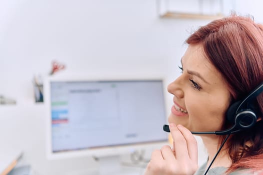 Friendly call center agent answering incoming calls with a headset, providing customer service remotely. Happy woman using her excellent communication skills to resolves customer issues.