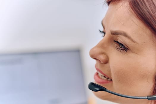 Friendly call center agent answering incoming calls with a headset, providing customer service remotely. Happy woman using her excellent communication skills to resolves customer issues.