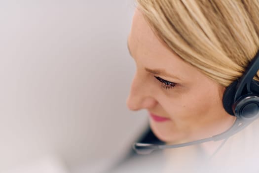 Friendly call center agent answering incoming calls with a headset, providing customer service remotely. Happy woman using her excellent communication skills to resolves customer issues.