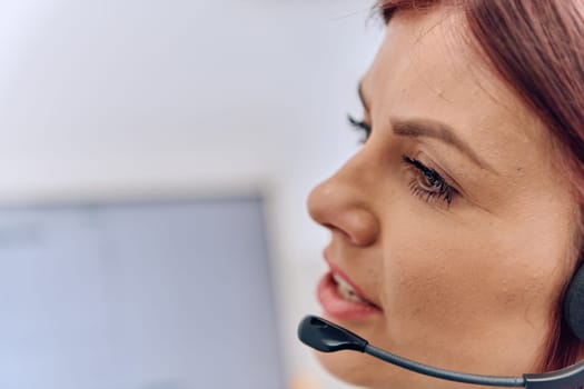 Friendly call center agent answering incoming calls with a headset, providing customer service remotely. Happy woman using her excellent communication skills to resolves customer issues.