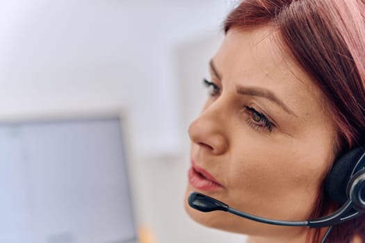 Friendly call center agent answering incoming calls with a headset, providing customer service remotely. Happy woman using her excellent communication skills to resolves customer issues.