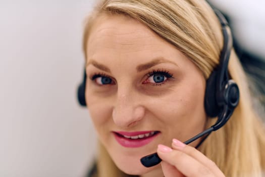 Friendly call center agent answering incoming calls with a headset, providing customer service remotely. Happy woman using her excellent communication skills to resolves customer issues.