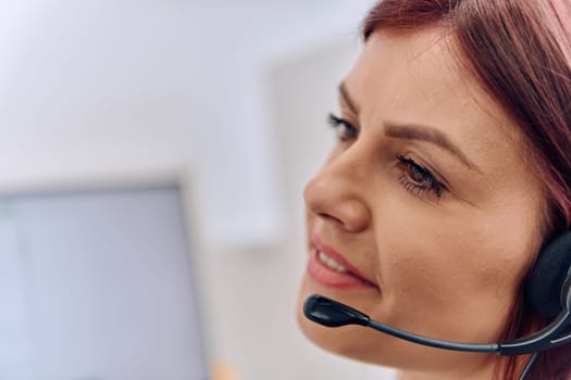 Friendly call center agent answering incoming calls with a headset, providing customer service remotely. Happy woman using her excellent communication skills to resolves customer issues.