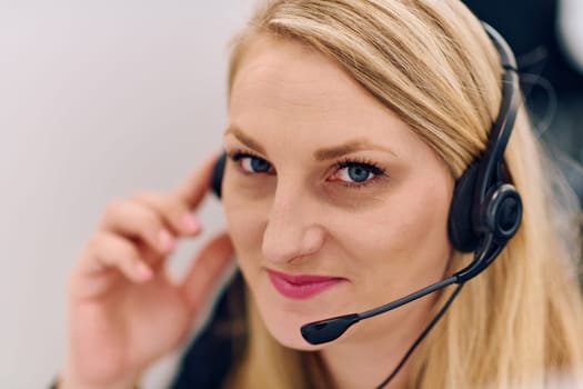 Friendly call center agent answering incoming calls with a headset, providing customer service remotely. Happy woman using her excellent communication skills to resolves customer issues.