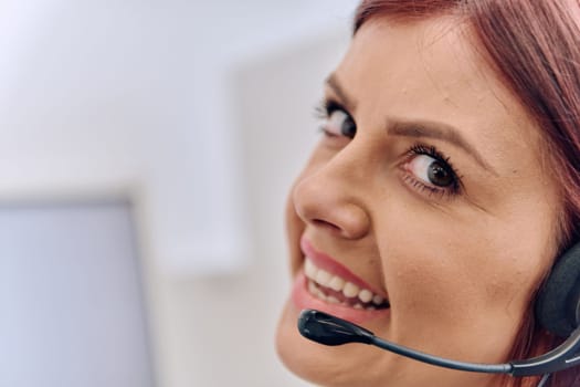 Friendly call center agent answering incoming calls with a headset, providing customer service remotely. Happy woman using her excellent communication skills to resolves customer issues.