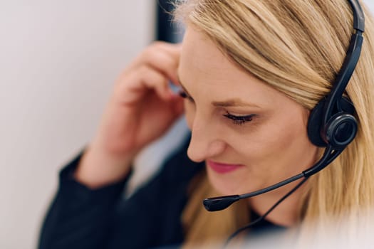 Friendly call center agent answering incoming calls with a headset, providing customer service remotely. Happy woman using her excellent communication skills to resolves customer issues.