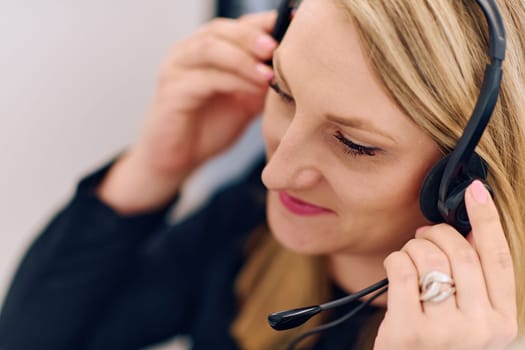 Friendly call center agent answering incoming calls with a headset, providing customer service remotely. Happy woman using her excellent communication skills to resolves customer issues.