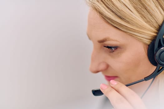 Friendly call center agent answering incoming calls with a headset, providing customer service remotely. Happy woman using her excellent communication skills to resolves customer issues.