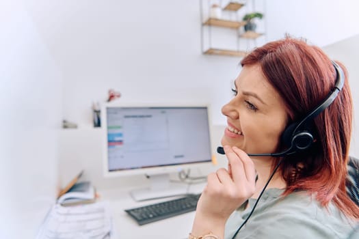 Friendly call center agent answering incoming calls with a headset, providing customer service remotely. Happy woman using her excellent communication skills to resolves customer issues.