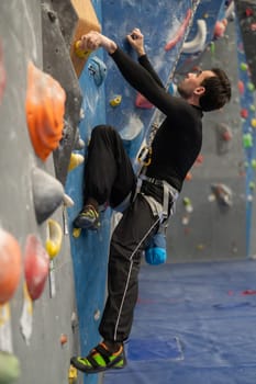 Caucasian man training on a climbing wall. Vertical photo