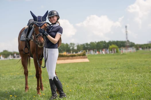 A young girl stands next to a horse before an equestrian competition