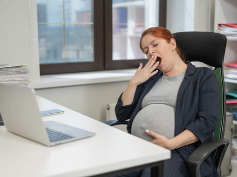 Pregnant woman sleeping at her desk in the office