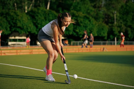 girl hockey player plays field hockey on a sunny day, female hockey player hits the ball with a stick, field hockey concept