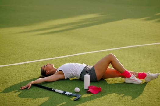 girl hockey player plays field hockey on a sunny day, hockey player drinks water during a break in the match, active sport for girls