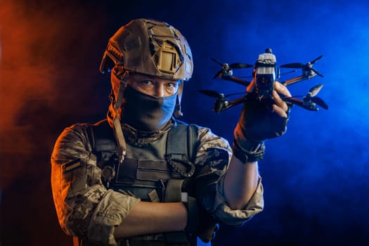 Soldier in gear holds drone against a red and blue smoky background, conveying intensity and military action