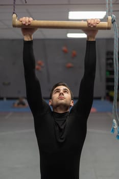 Caucasian man doing pull-ups on trapeze. Warm-up before the climbing wall