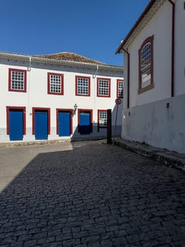 Traditional house with blue doors and windows, set on a cobblestone street during the day.