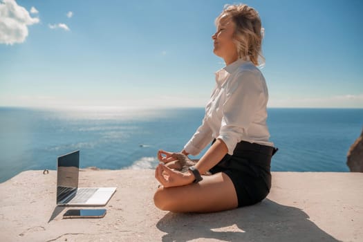 Freelance women sea working on the computer. Good looking middle aged woman typing on a laptop keyboard outdoors with a beautiful sea view. The concept of remote work