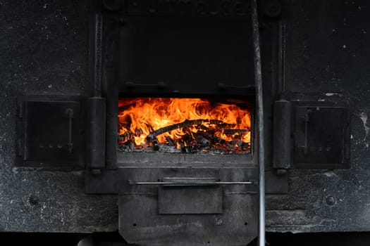 Rustic wood oven glowing with flames. Red fire in black oven.