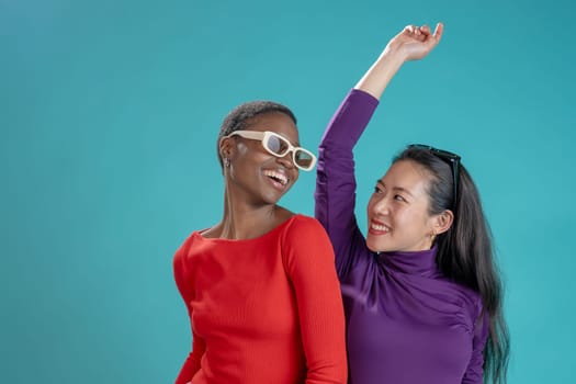 Two happy women pose on blue studio background. High quality photo