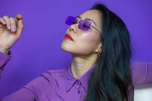 Cheerful lady with sunglasses pose isolated over violet background. High quality photo