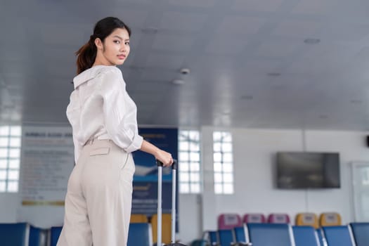 Confident businesswoman standing in a contemporary airport terminal, holding luggage and ready for travel. Ideal for business travel, corporate, and transportation themes.