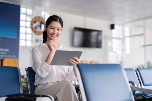 A business professional uses a tablet in a modern airport lounge, showcasing technology and travel in a professional setting.