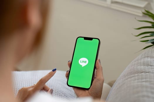 Woman holding Apple iPhone 14 with LINE apps on screen. LINE is a new communication app which allows you to make free voice calls and send free messages