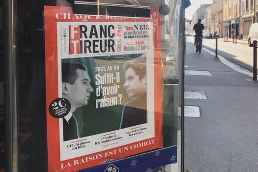 PARIS, FRANCE - JUNE 25, 2024: Magazine banner of Franc Tireurin with Jordan Bardella and Attal in a kiosk with newspapers and magazines