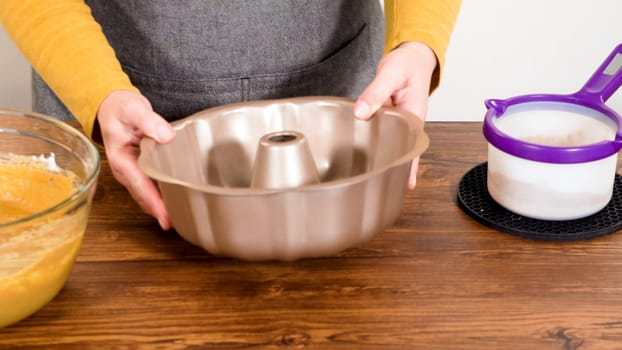 Carefully greasing a bundt cake pan in preparation for baking a delicious gingerbread bundt cake with caramel frosting.