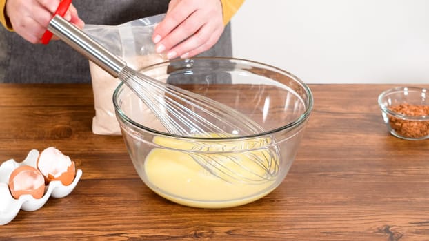 In a glass mixing bowl, a large hand whisk expertly blends the ingredients for a delectable gingerbread bundt cake with caramel frosting.