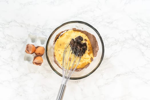 Flat lay. In the process of creating mouthwatering chocolate cupcakes, the first step involves meticulously mixing the ingredients in a glass mixing bowl to make the perfect batter.