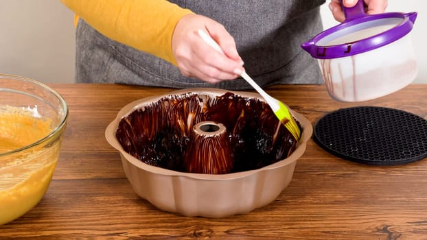 Carefully greasing a bundt cake pan in preparation for baking a delicious gingerbread bundt cake with caramel frosting.