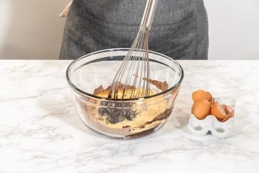 In the process of creating mouthwatering chocolate cupcakes, the first step involves meticulously mixing the ingredients in a glass mixing bowl to make the perfect batter.