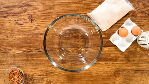 Flat lay. In a glass mixing bowl, a large hand whisk expertly blends the ingredients for a delectable gingerbread bundt cake with caramel frosting.