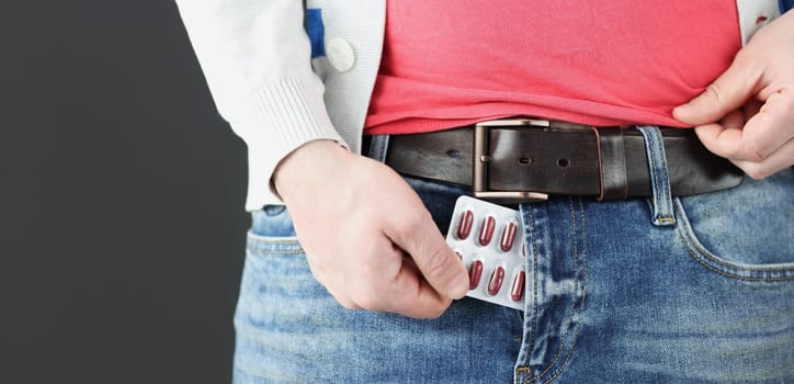 Man takes male pills out of fly of his pants. Erectile function problems concept