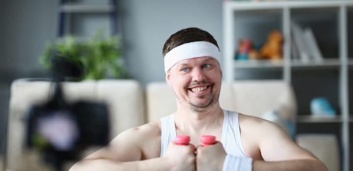 Smiling male blogger recording physical exercises on camera, Online sports activities in quarantine concept