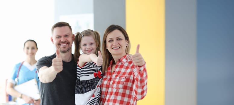 Parents and little girl showing thumbs up at doctor appointment. Family medicine concept