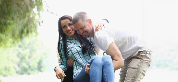 Man picks up smiling woman from wheelchair. Support and support for people with disabilities concept